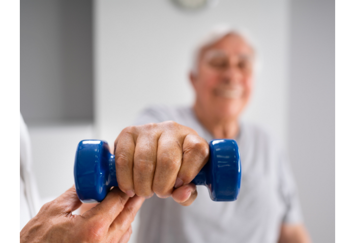 Older man lifting dumbbell with help from PT